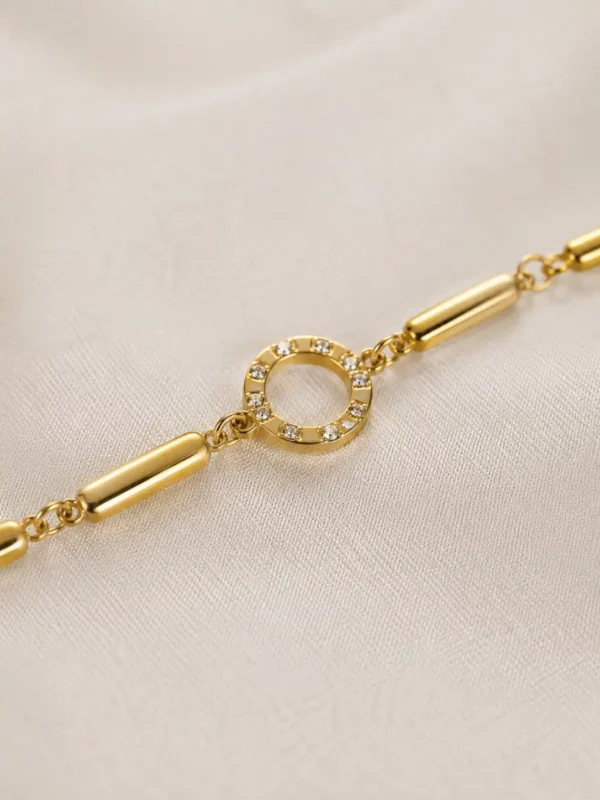 Close-up of Aurelia gold bracelet showing crystal-studded circular halo centre and polished links