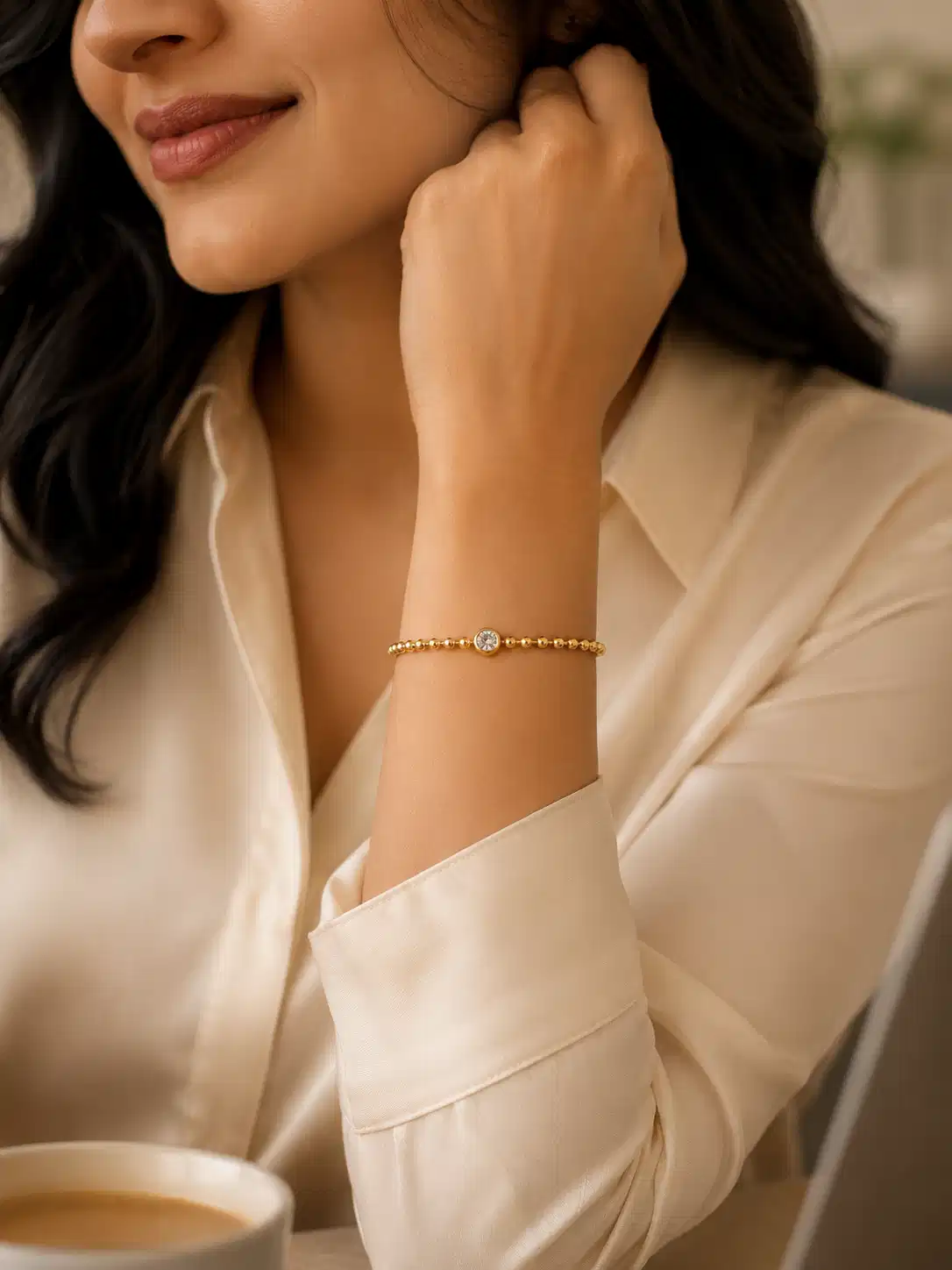 Woman wearing Elara gold solitaire bead bracelet with neutral office wear