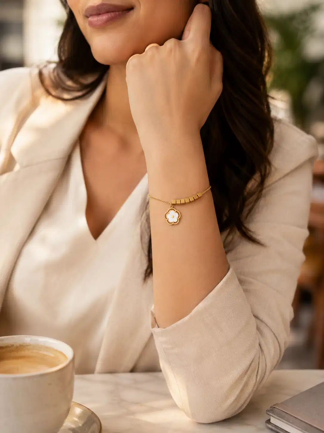 Woman wearing Avira anti-tarnish gold floral charm bracelet with cube accents for office wear