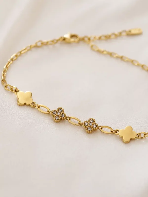 Close-up of gold clover bracelet with polished and crystal-studded clover charms