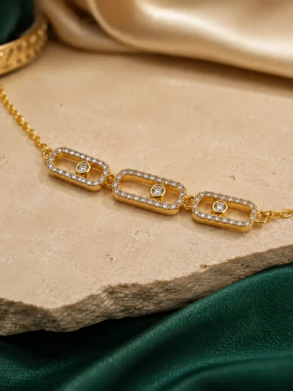 Close-up of three crystal-pavé rectangular links with round centre stones on gold-tone bracelet