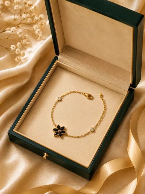 Noir Bloom black flower charm bracelet displayed in an open green and cream jewellery box