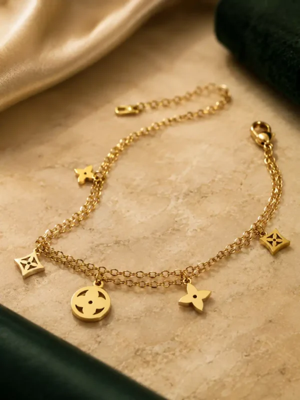 Anti-tarnish gold double-layer bracelet with circular, square and four-petal dangling charms on stone surface