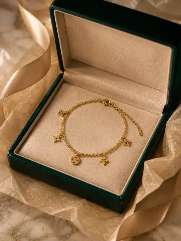 Anti-tarnish double-layer gold charm bracelet displayed in green jewellery box with dangling cutout charms
