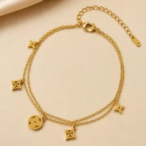 Gold-toned double-layer charm bracelet with geometric clover and circular cutout charms, lobster clasp and extension chain