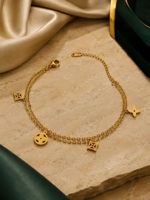 Double-chain gold charm bracelet with multiple geometric dangling motifs and adjustable lobster clasp