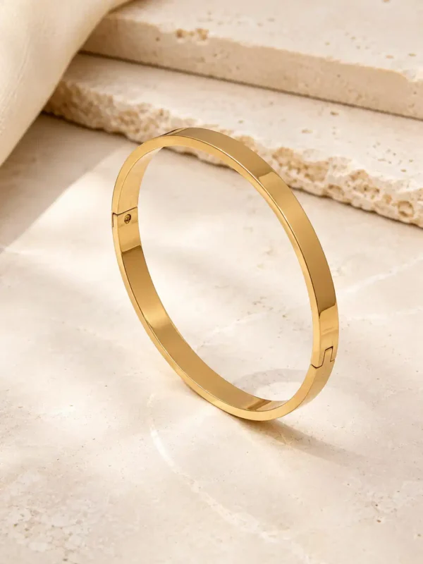 Sleek gold-plated bangle bracelet standing upright showing smooth flat profile