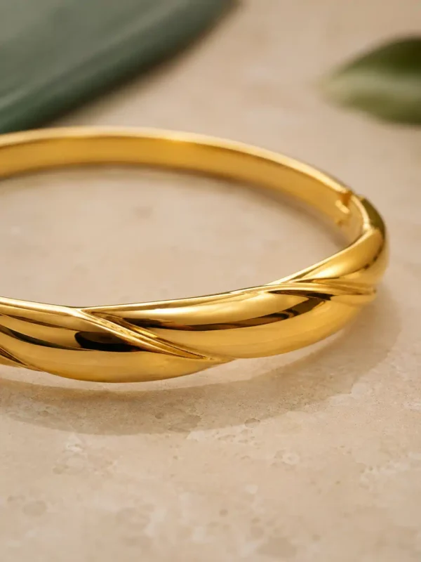 Close-up of the polished overlapping twist detail on an anti-tarnish gold bangle