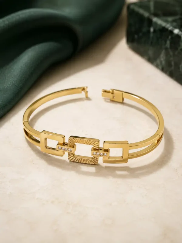 Open anti-tarnish gold bangle showing geometric rectangular links and clasp