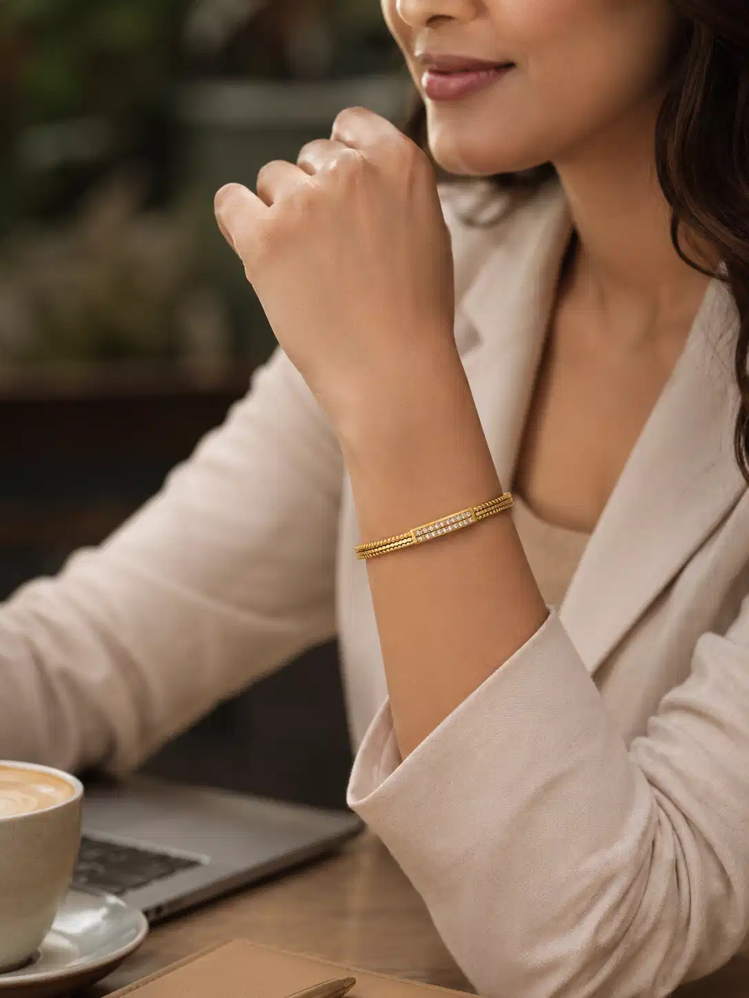 Woman wearing anti-tarnish gold crystal bangle with beige office blazer