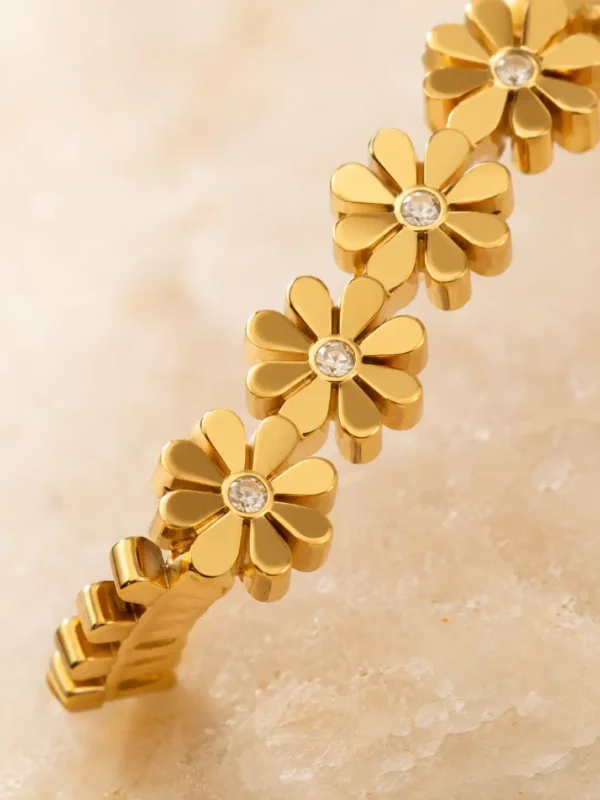 Close-up of gold daisy flowers with sparkling centre stones on Daisy Glow bangle