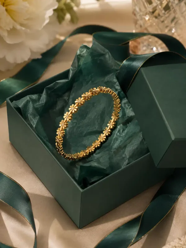 Daisy Glow gold daisy bangle displayed in green jewellery presentation box