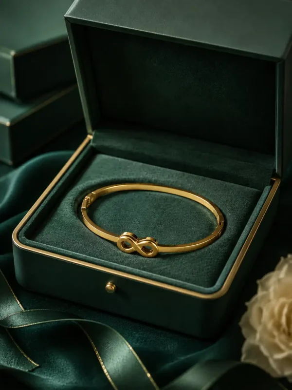 Gold infinity bracelet displayed inside a dark green jewellery box