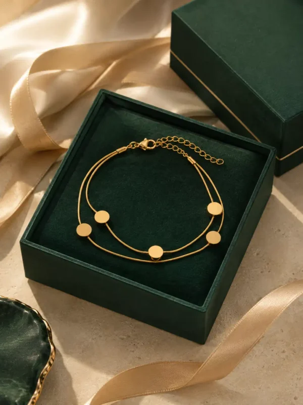 Golden Orbit gold-toned double-strand disc bracelet presented in a dark green jewellery gift box