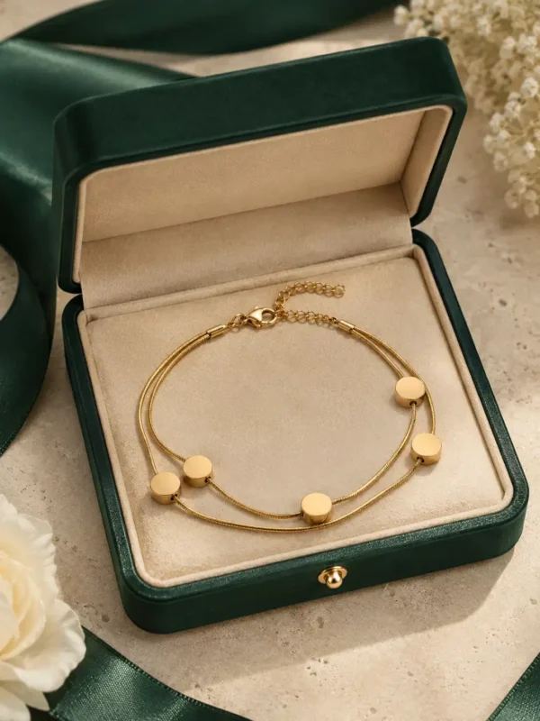 Golden Orbit double-strand disc bracelet displayed inside an open green jewellery box