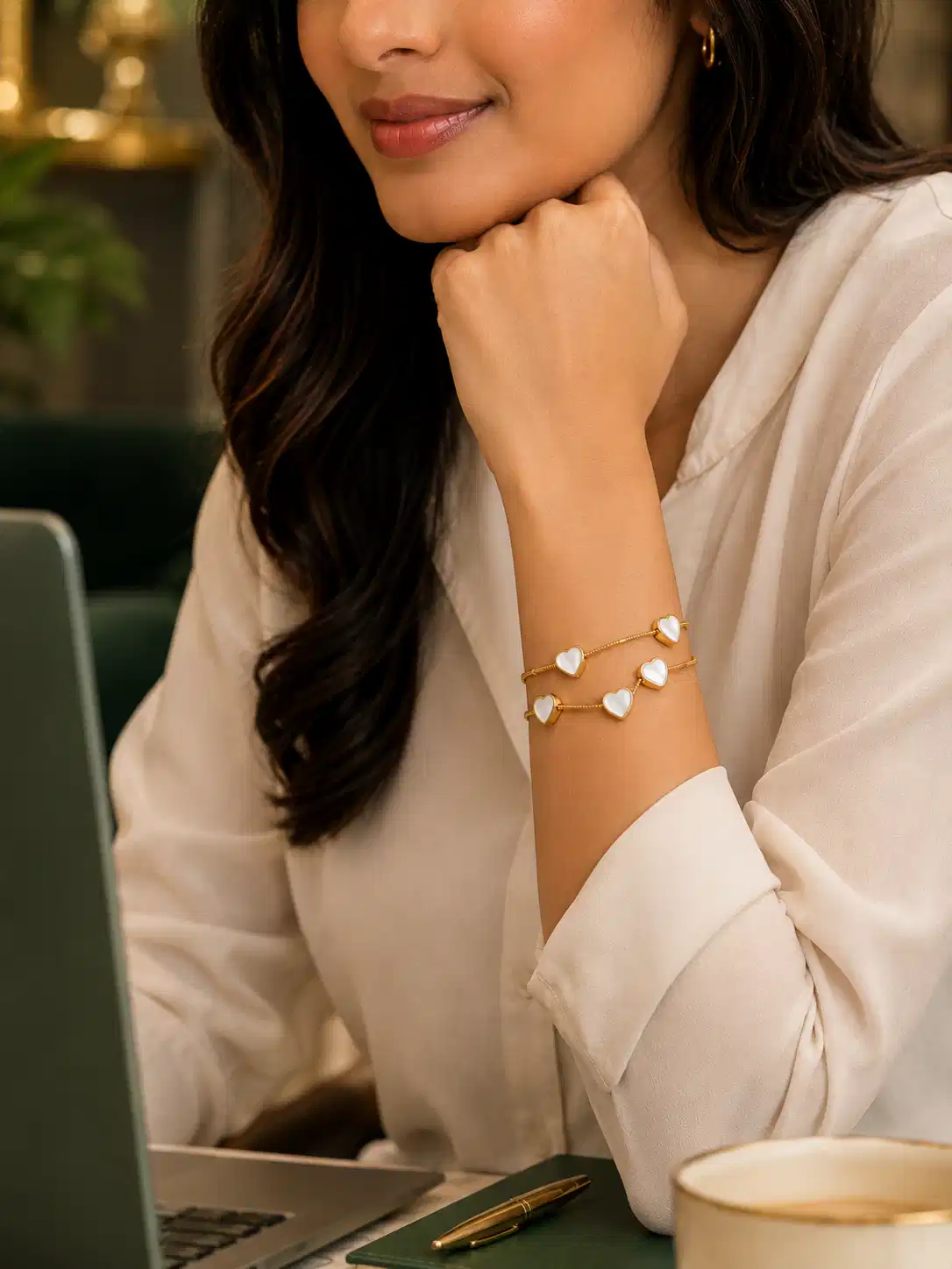 Woman wearing gold double-strand mother-of-pearl heart bracelet with office outfit