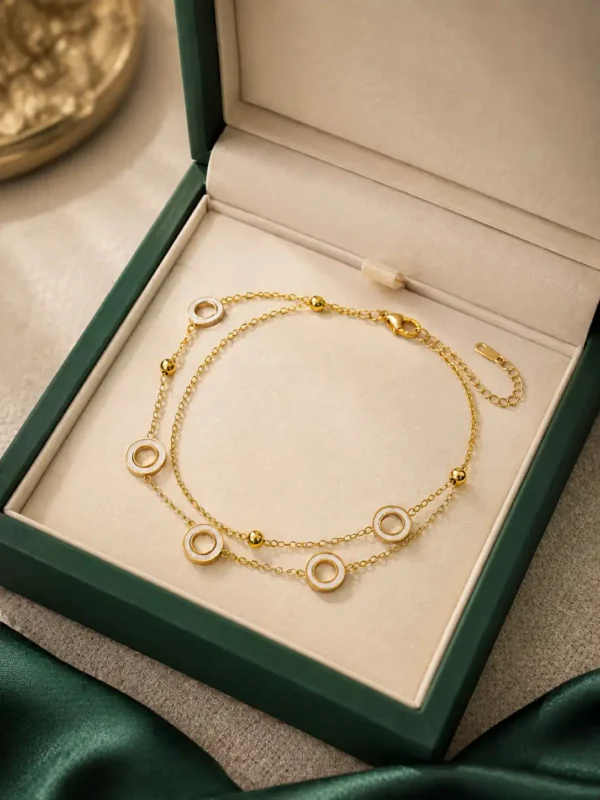 Ivory Orbit gold double-layer bracelet displayed in green jewellery box