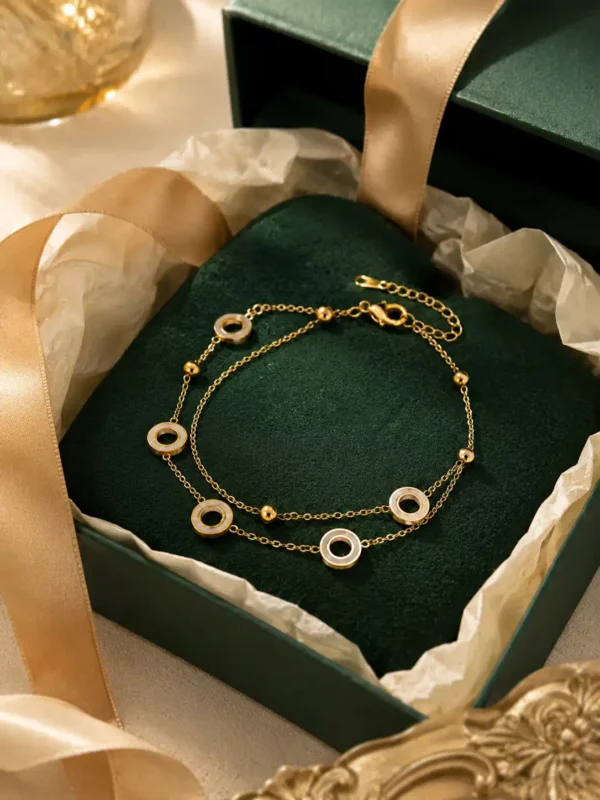 Gold double-layer circle charm bracelet displayed in dark green gift box