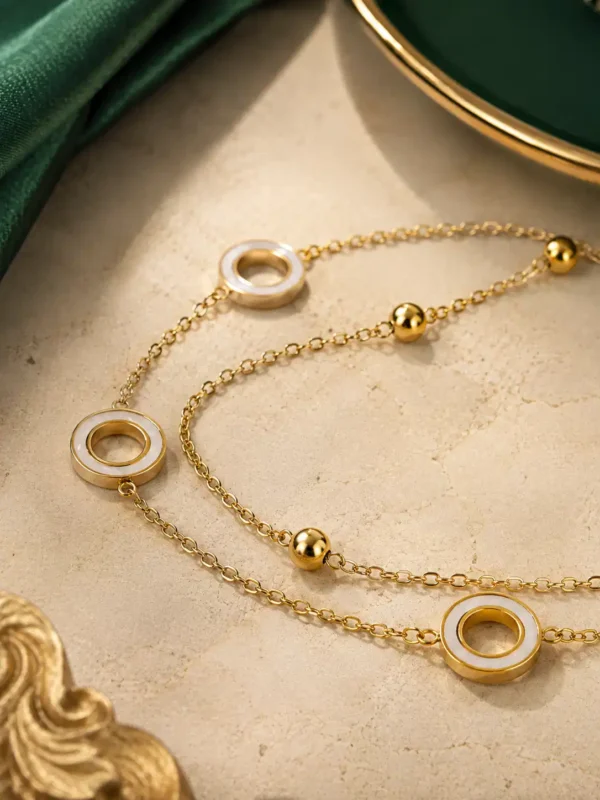 Close-up of gold bracelet with white circular inlay charms and small polished beads