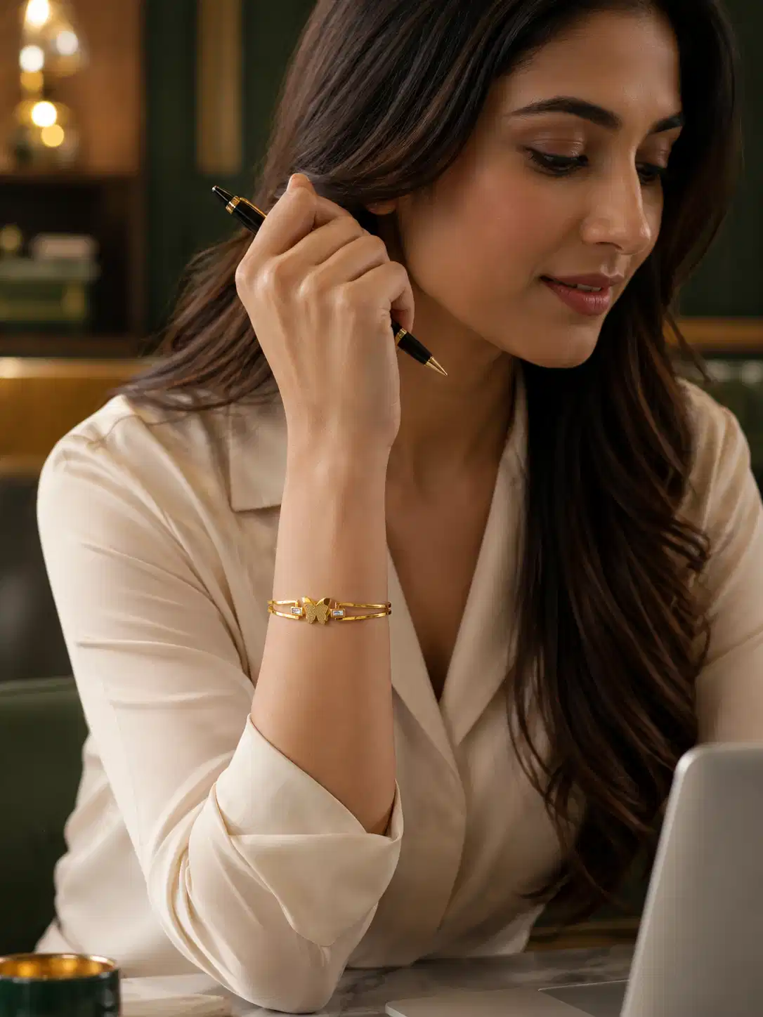 Woman wearing a gold butterfly bangle with crystal accents as minimal office wear jewellery