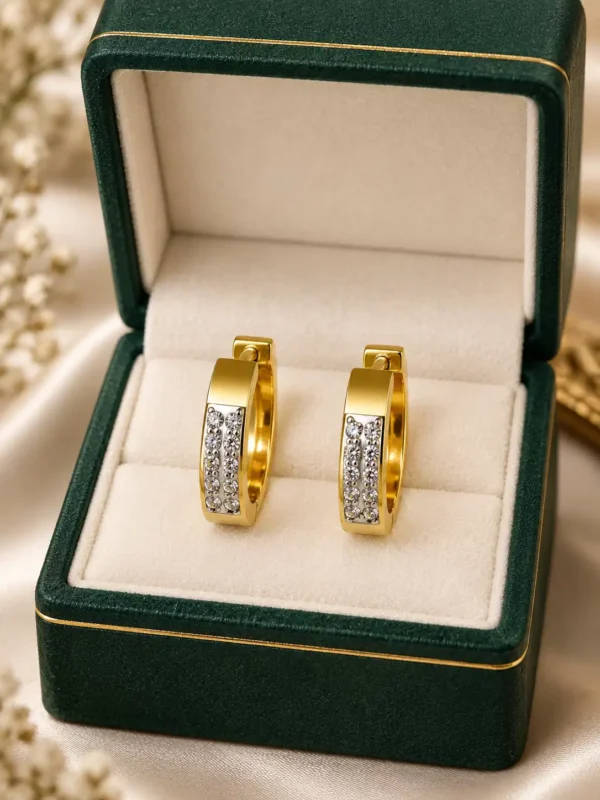 Gold crystal huggie hoop earrings displayed in green jewellery box
