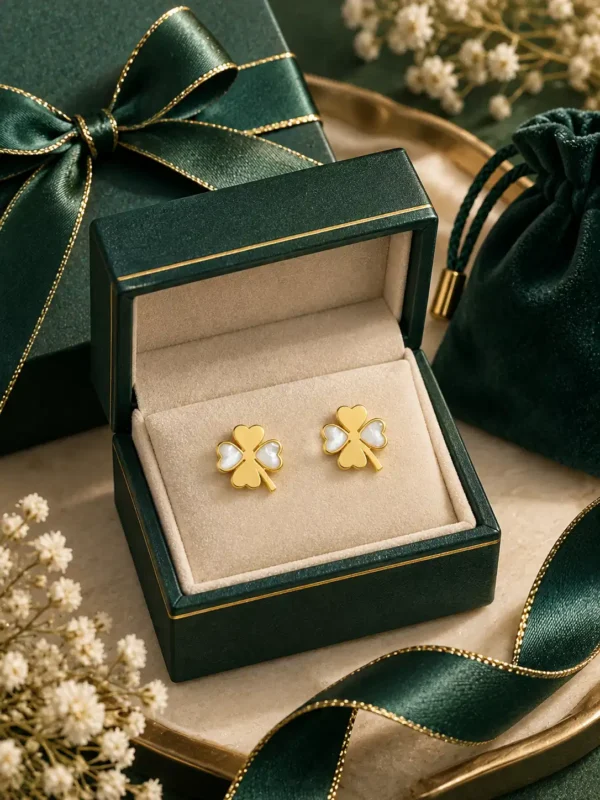 Gold and white clover stud earrings presented in a green jewellery gift box