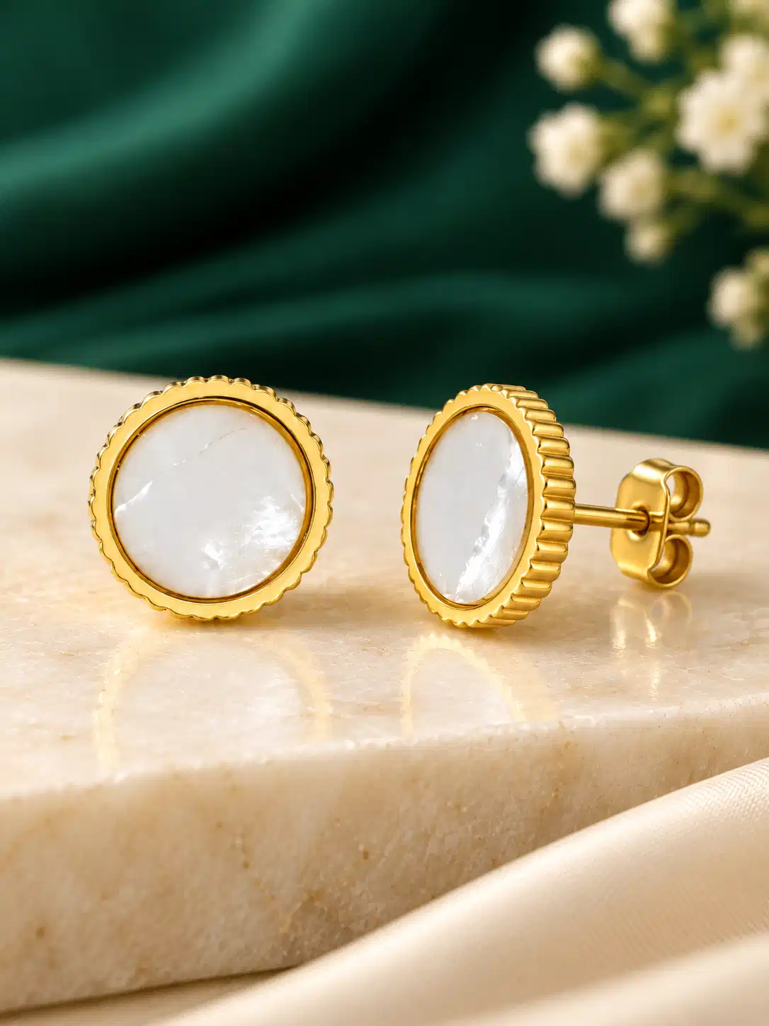 Round mother-of-pearl gold stud earrings displayed inside green jewellery box
