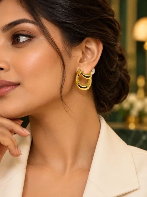 Woman wearing 2 cm gold pearl swirl stud earrings with an ivory blazer