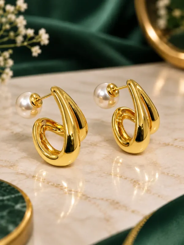 Angled view of gold-plated pearl swirl earrings showing sculpted design and pearl backs