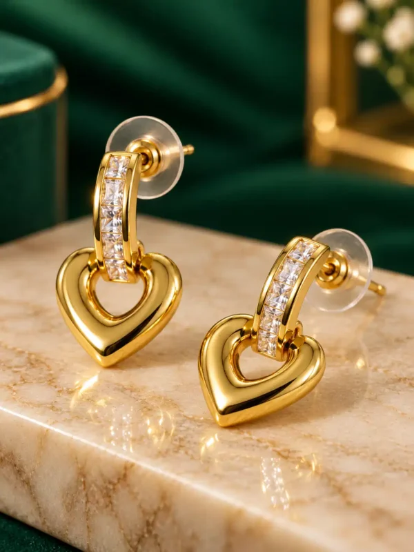 Close-up of gold heart drop earrings with clear crystal-set tops