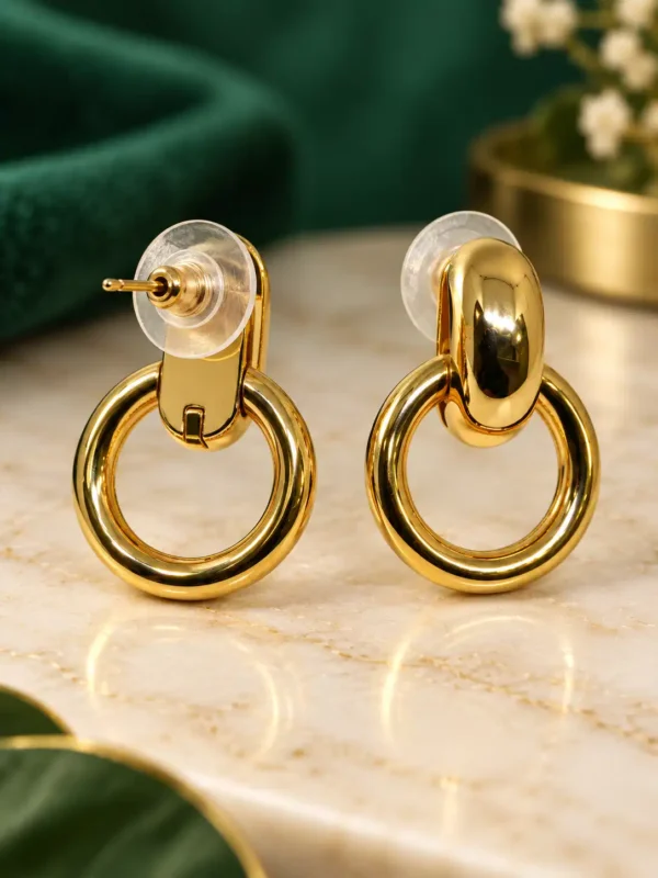 Close-up of gold heart drop earrings with clear crystal-set tops