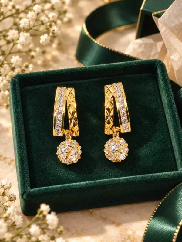 Gold crystal sphere drop earrings displayed on emerald velvet with geometric crystal detailing