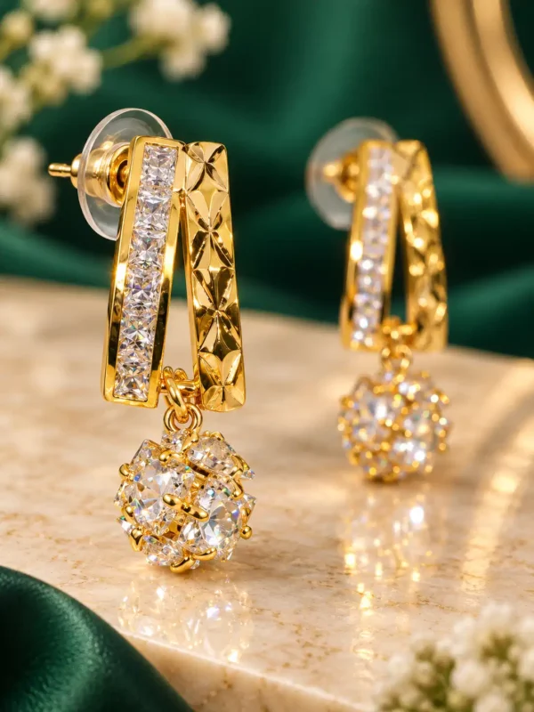 Close-up of gold geometric crystal earring with faceted detailing and dangling crystal spherE