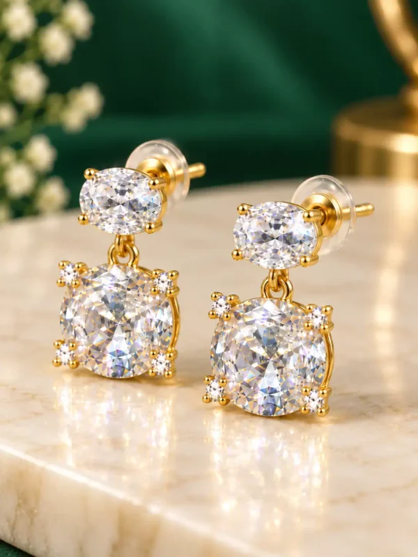 Close-up of gold-plated double crystal earrings with oval and round clear stones