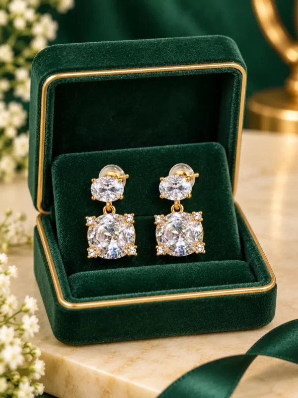 Gold-plated double crystal drop earrings presented inside a green velvet jewellery box
