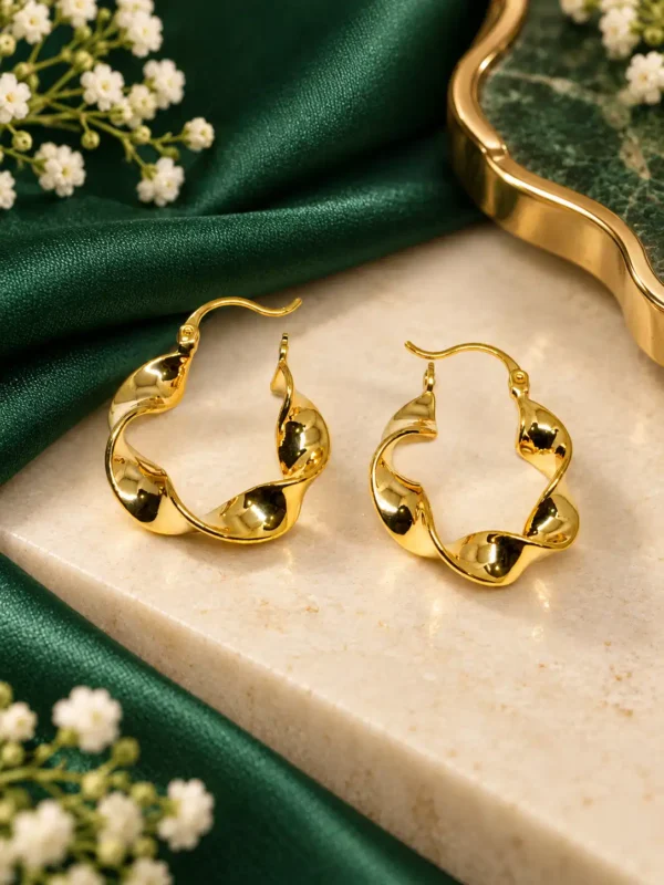 Close-up of sculpted gold twist hoop earrings with polished wavy curves