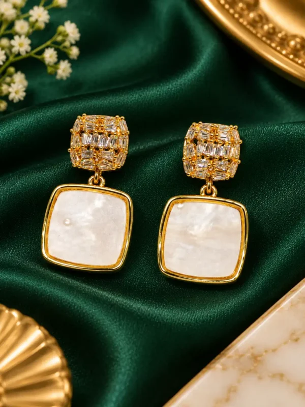 Gold crystal and white pearl-effect square drop earrings on green satin