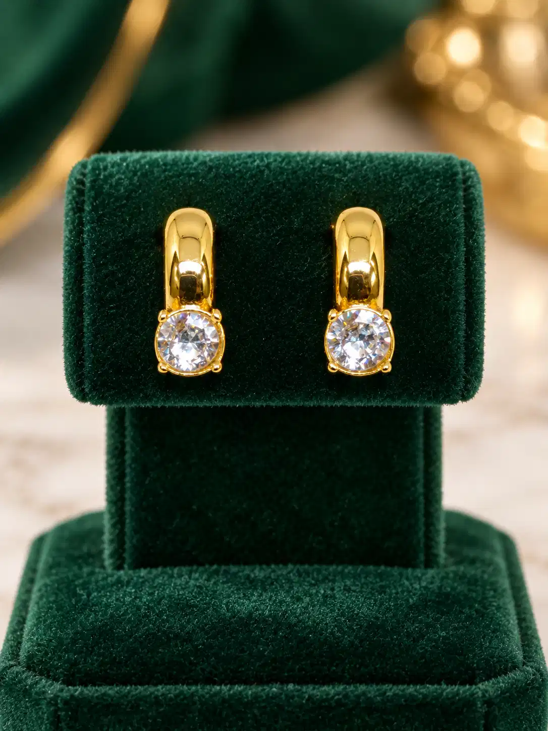 Pair of anti-tarnish gold ear cuffs with round solitaire CZ stones on green velvet display