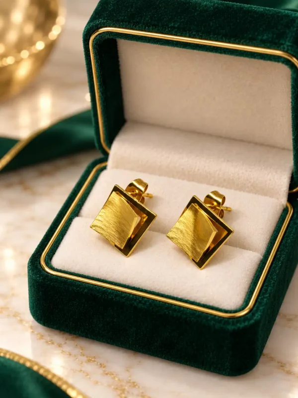 Quiet Power gold-tone square stud earrings displayed in green and cream jewellery box