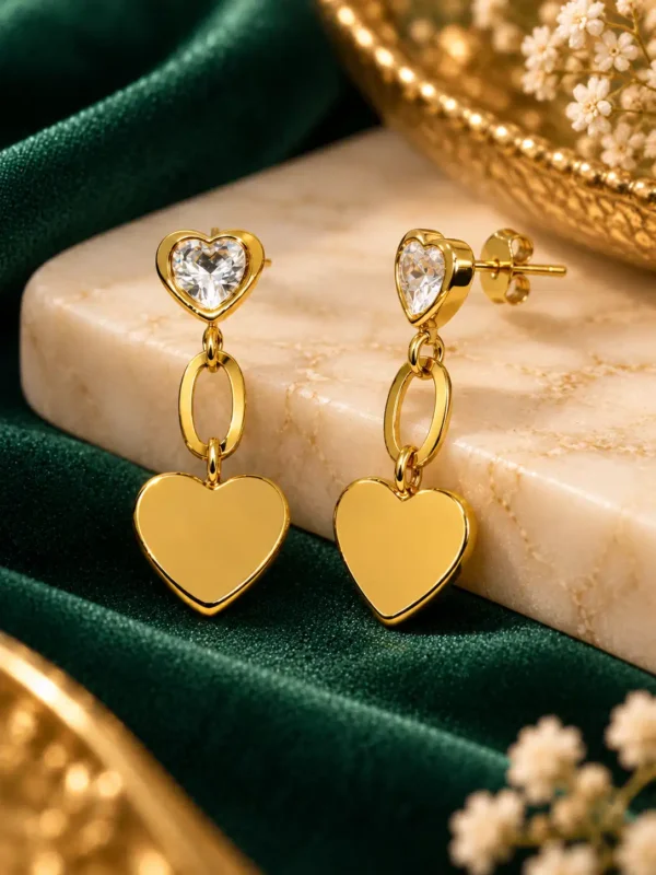 Close-up of gold-plated CZ heart drop earrings showing crystal heart studs, oval links and smooth heart charms