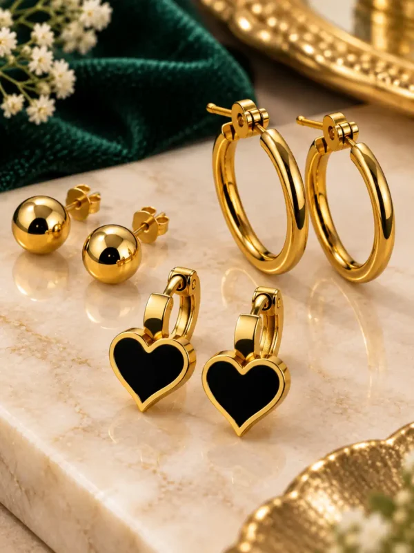 Close-up of gold hoops, black enamel heart earrings and polished ball studs