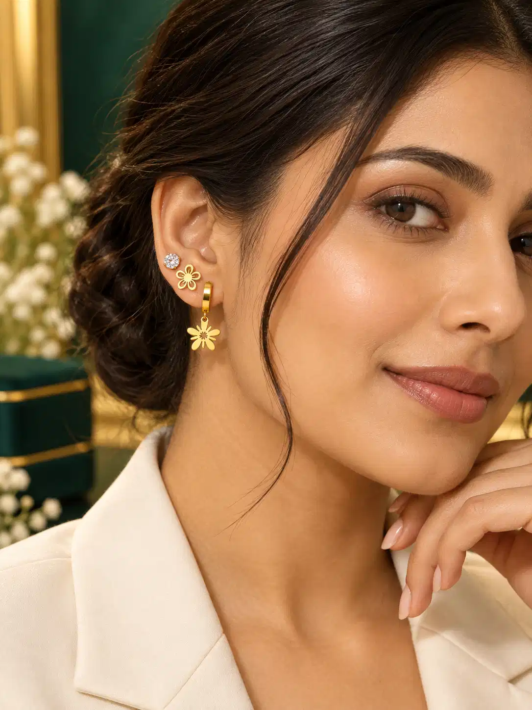 Woman wearing crystal stud, gold floral stud and floral drop hoop from a three-pair gold earring set