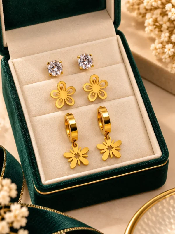 Three-pair gold earring set in jewellery box with crystal studs, flower studs and floral drop hoop earrings
