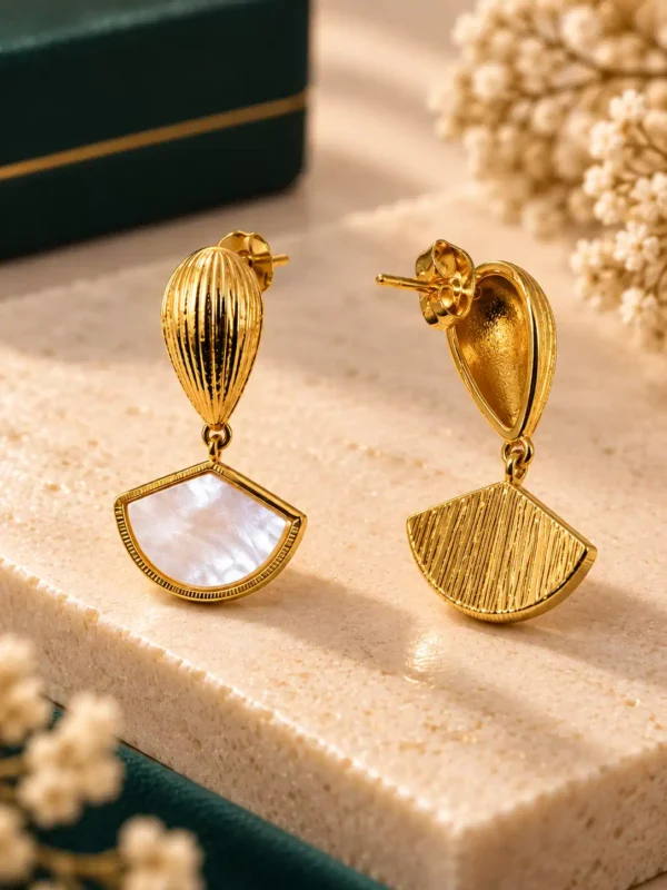 Close-up of gold shell fan earrings showing ridged top and textured back