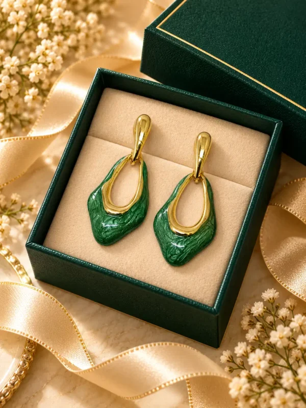 Green and gold statement drop earrings displayed in an emerald jewellery box