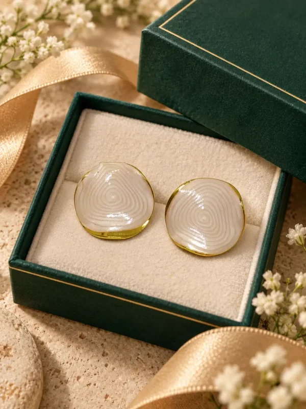 Pair of ivory marble-look anti-tarnish stud earrings displayed in cream and green jewellery box