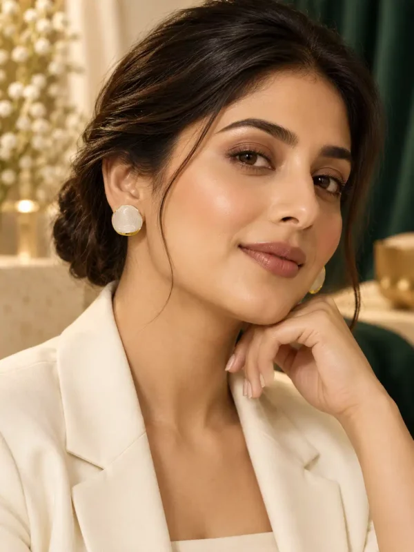 Woman wearing ivory marble-look stud earrings with gold-tone edging and white blazer for office wear