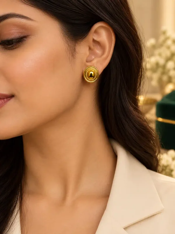 Woman wearing Aurelia anti-tarnish gold textured stud earrings with a white blazer