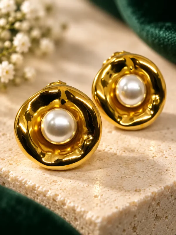Close-up of sculpted gold pearl stud earrings with white pearl centres