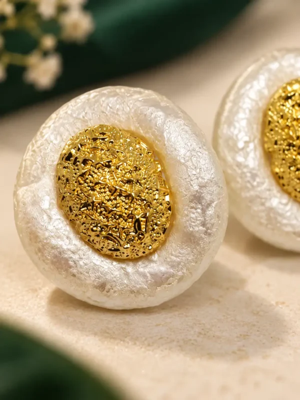 Close-up of textured gold centre and pearl-effect ivory finish on statement stud earrings